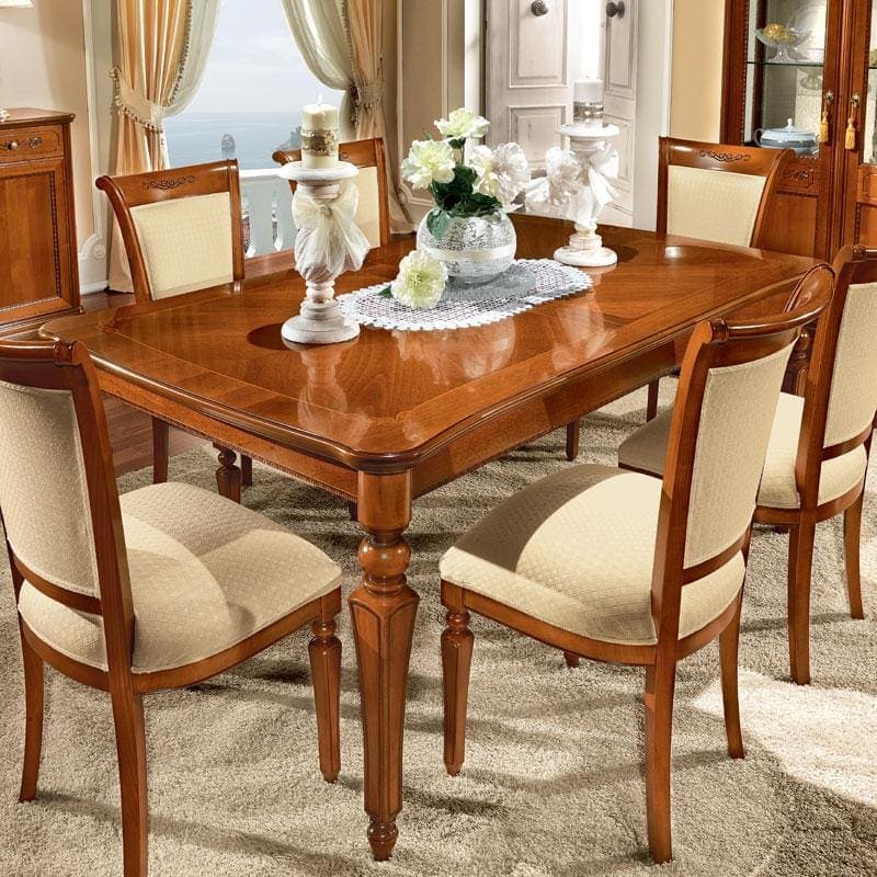 Close-up of the walnut Torriani dining table with chairs and carved detail.